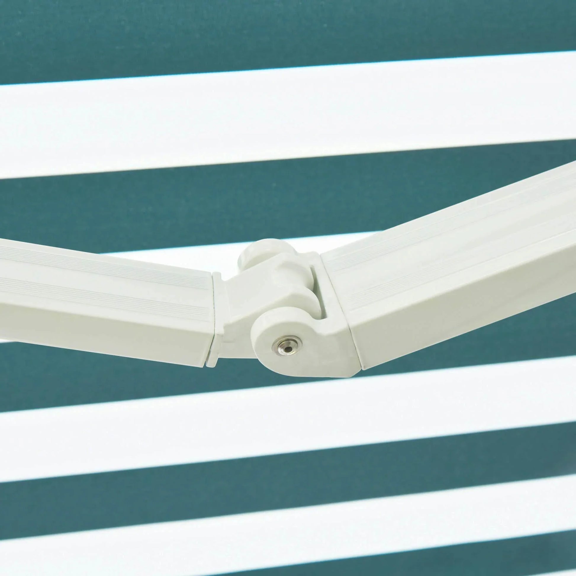 Close-up of white folding arm joint against green and white striped outdoor awning fabric