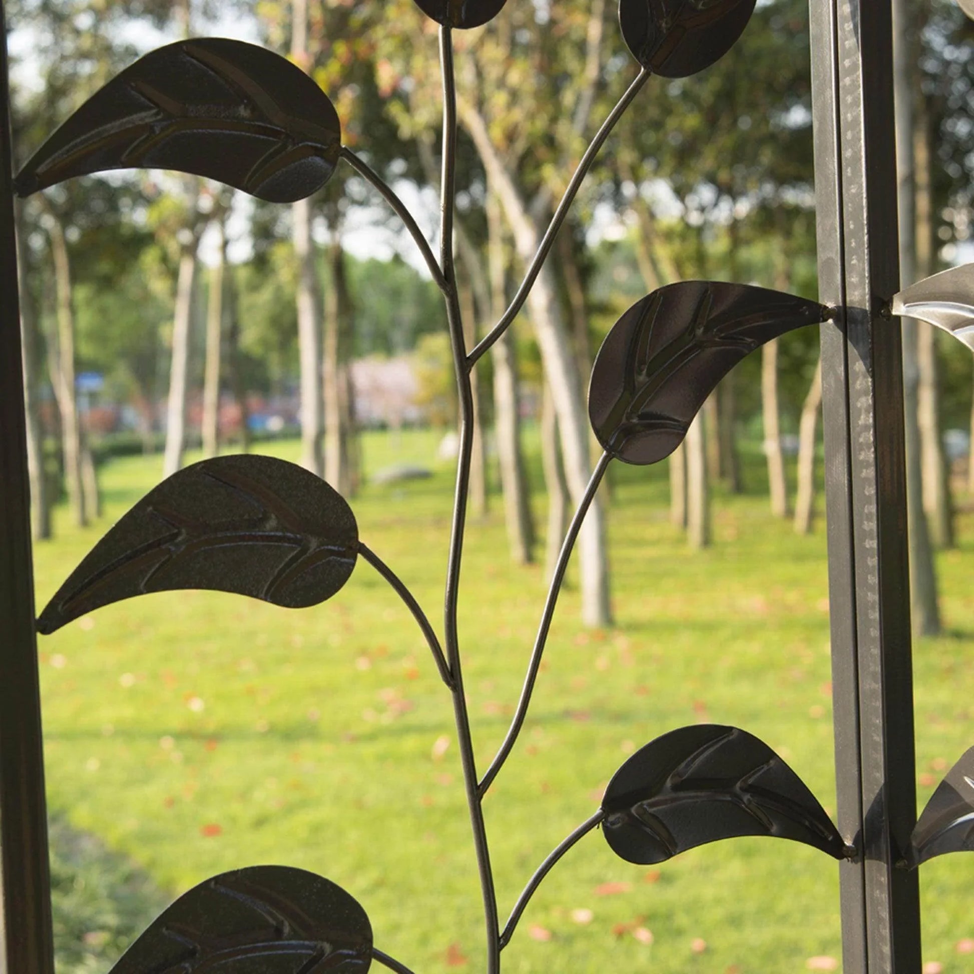 Close-up of decorative black metal leaf detail on beige outdoor gazebo frame in green park