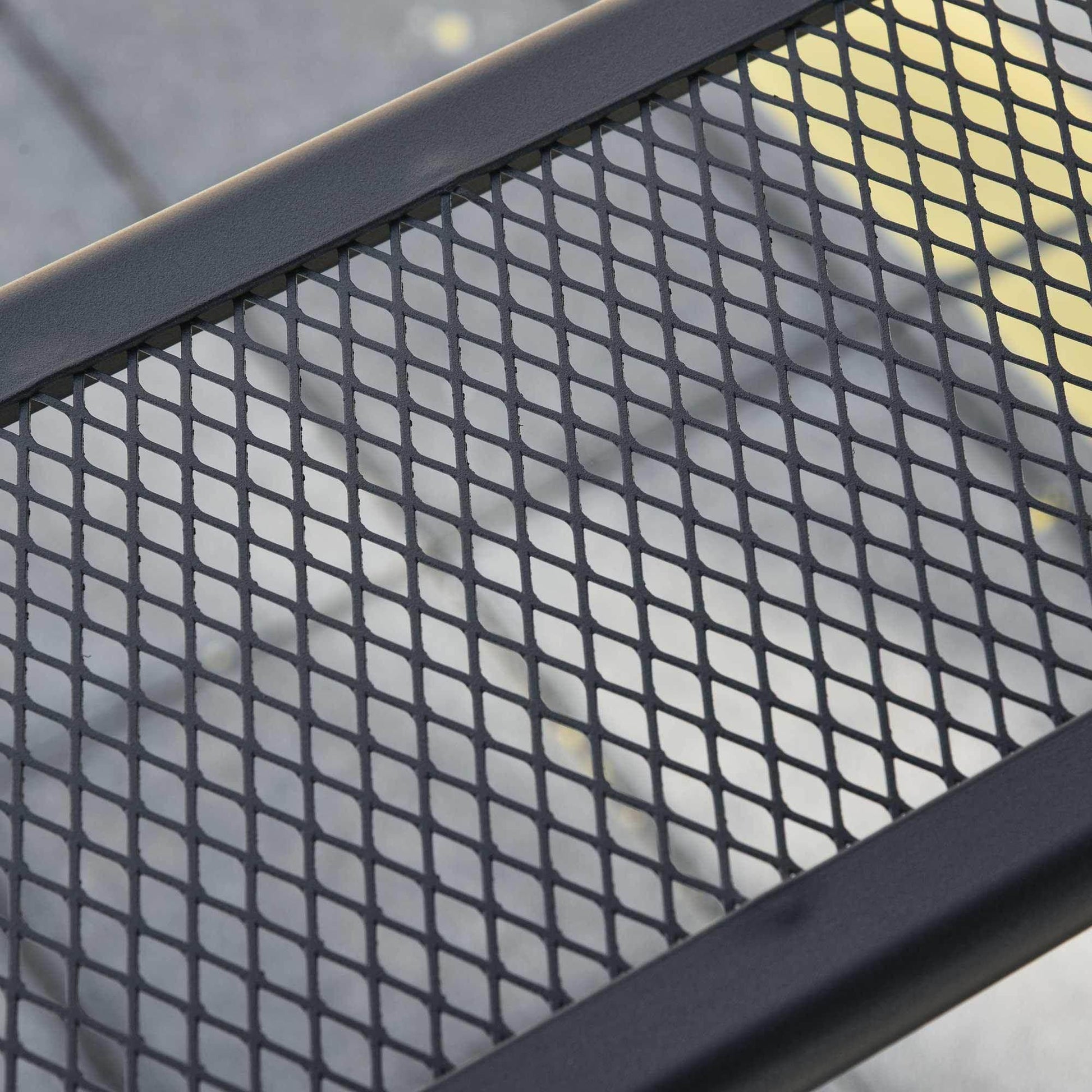 Close-up of black metal mesh tabletop with diamond pattern and sturdy frame for outdoor use
