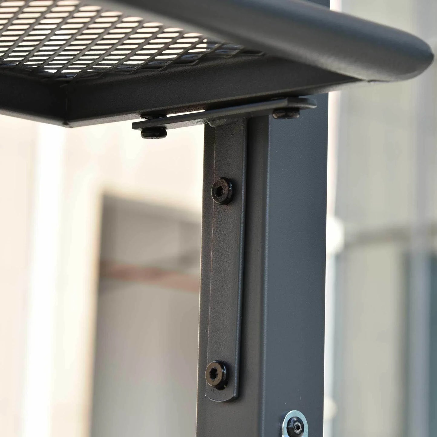 Close-up of black metal pole with screws and mesh shelf bracket detail