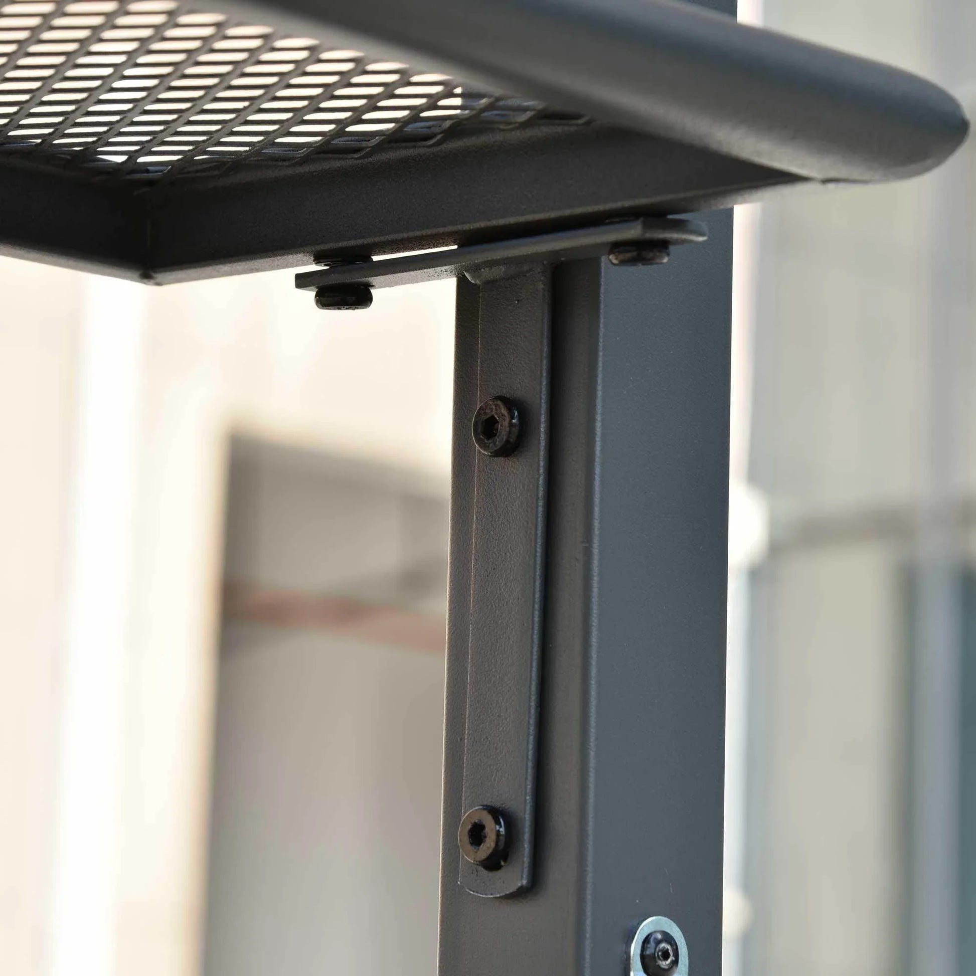 Close-up of black metal pole with screws and mesh shelf bracket detail