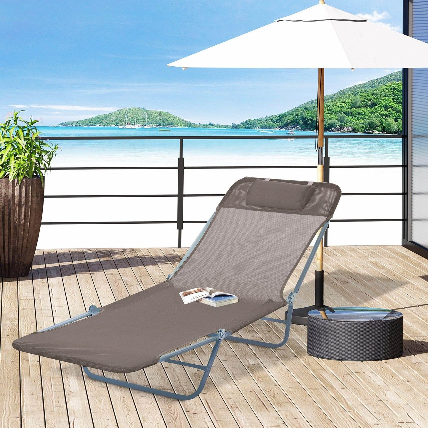 Coffee-colored mesh garden lounge chair with headrest on wooden deck under white umbrella with ocean view
