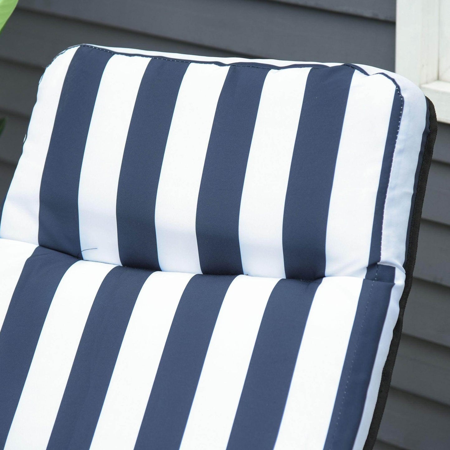 Close-up of navy and white striped padded cushion on outdoor patio recliner against gray siding