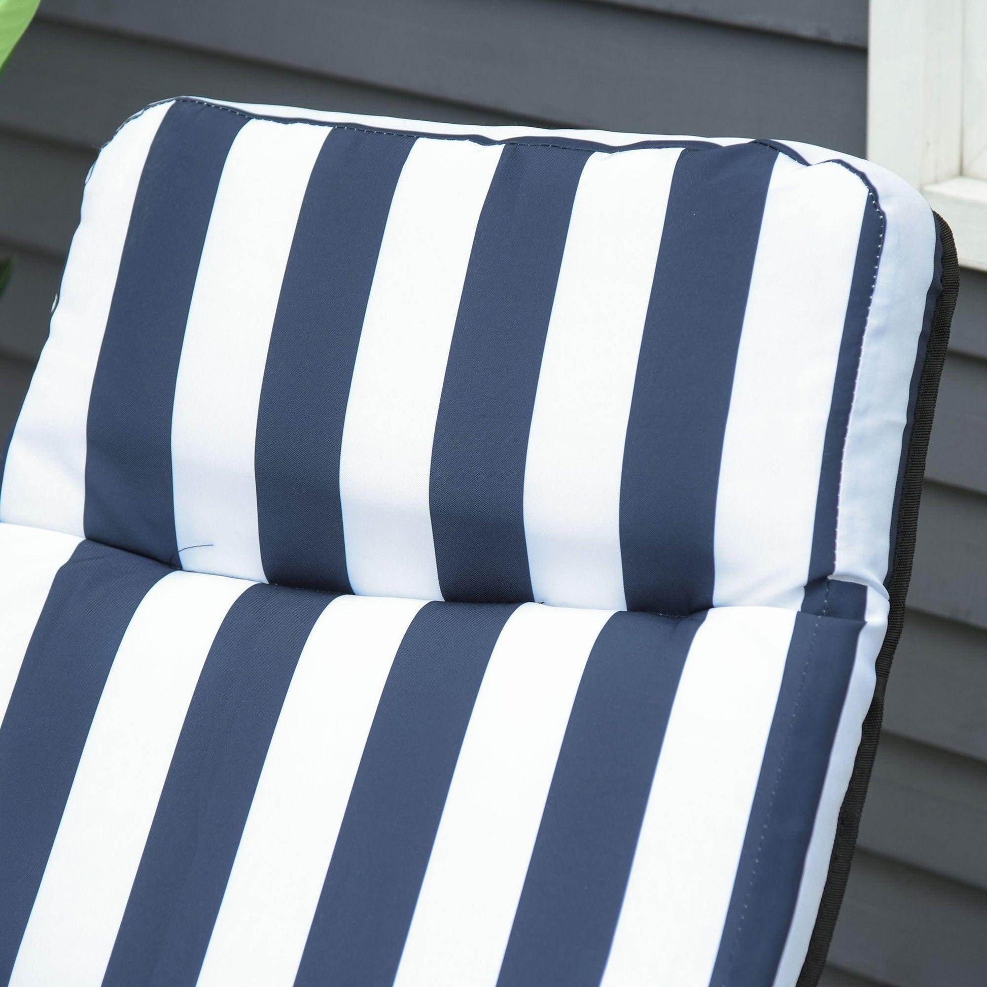 Close-up of navy and white striped padded cushion on outdoor patio recliner against gray siding
