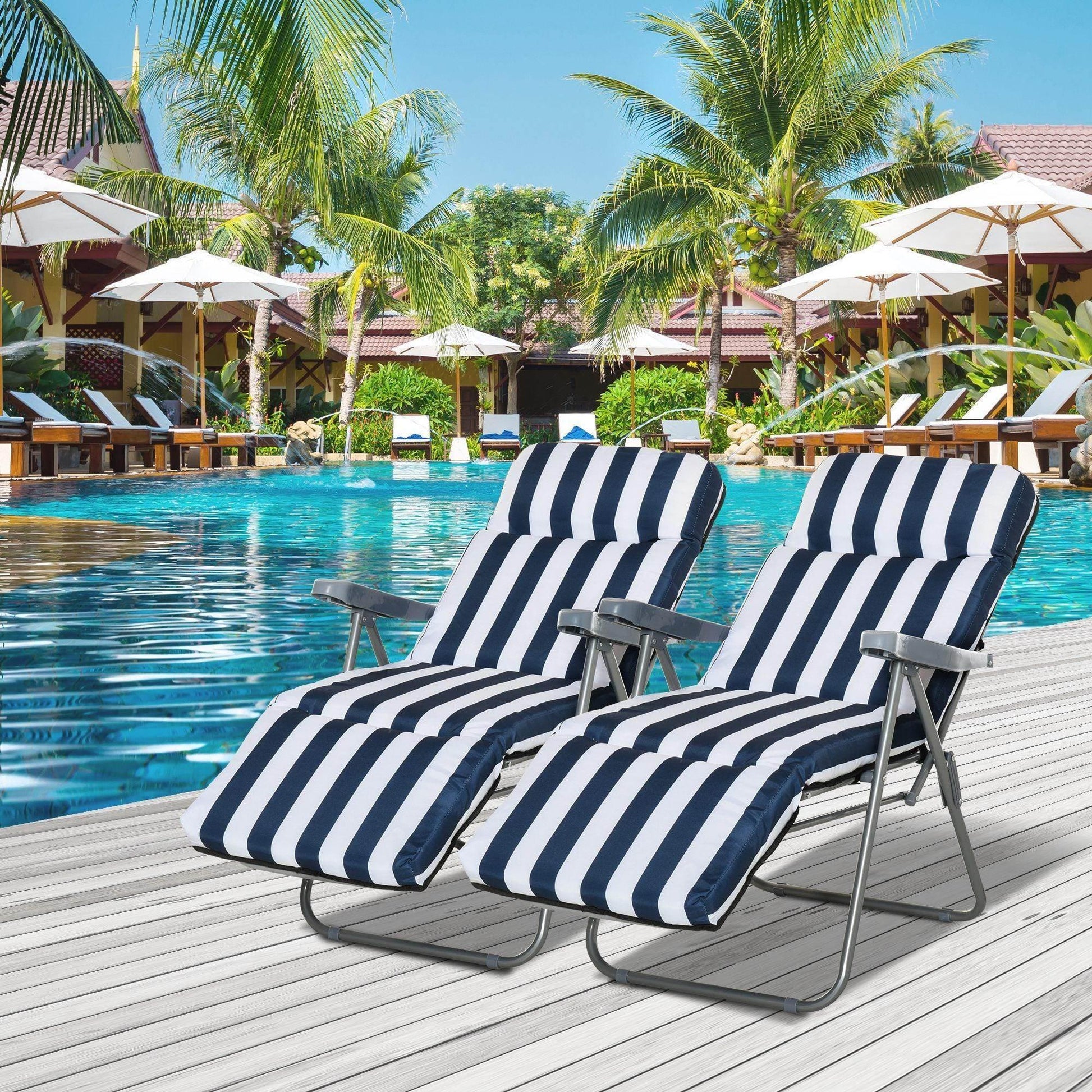Pair of navy blue and white striped outdoor sun recliners by poolside with palm trees and umbrellas