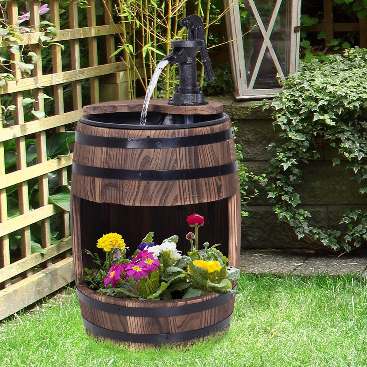 Wood barrel patio water fountain with black spout and flower planter filled with colorful blooms