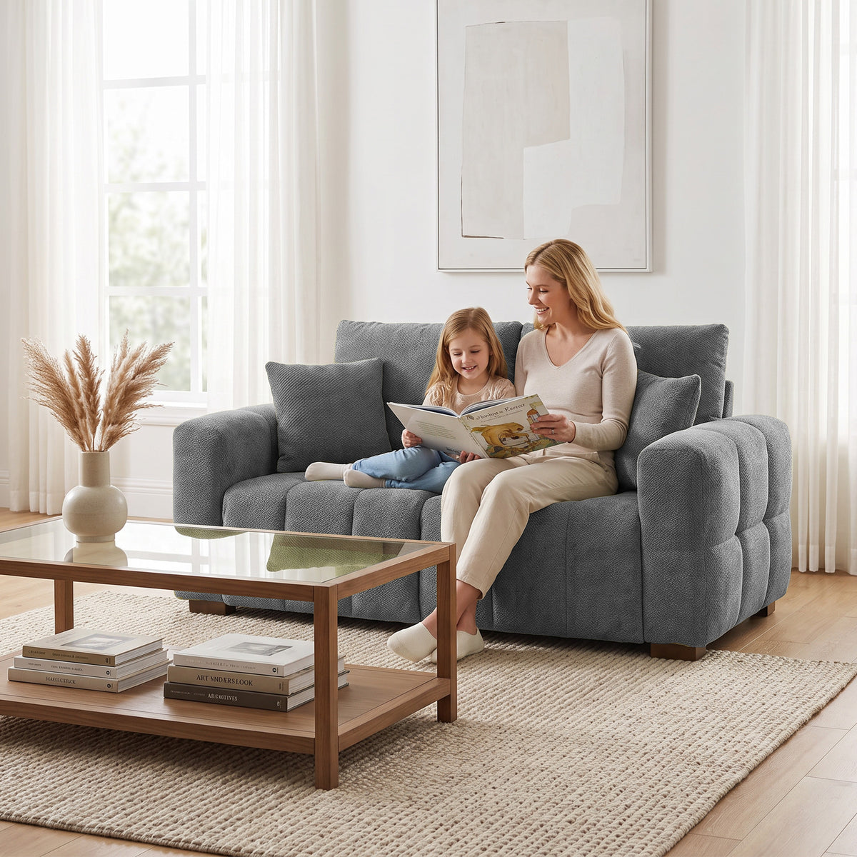 Grey 2-seater velvet sofa with pillows and rounded arms, shown in a room.