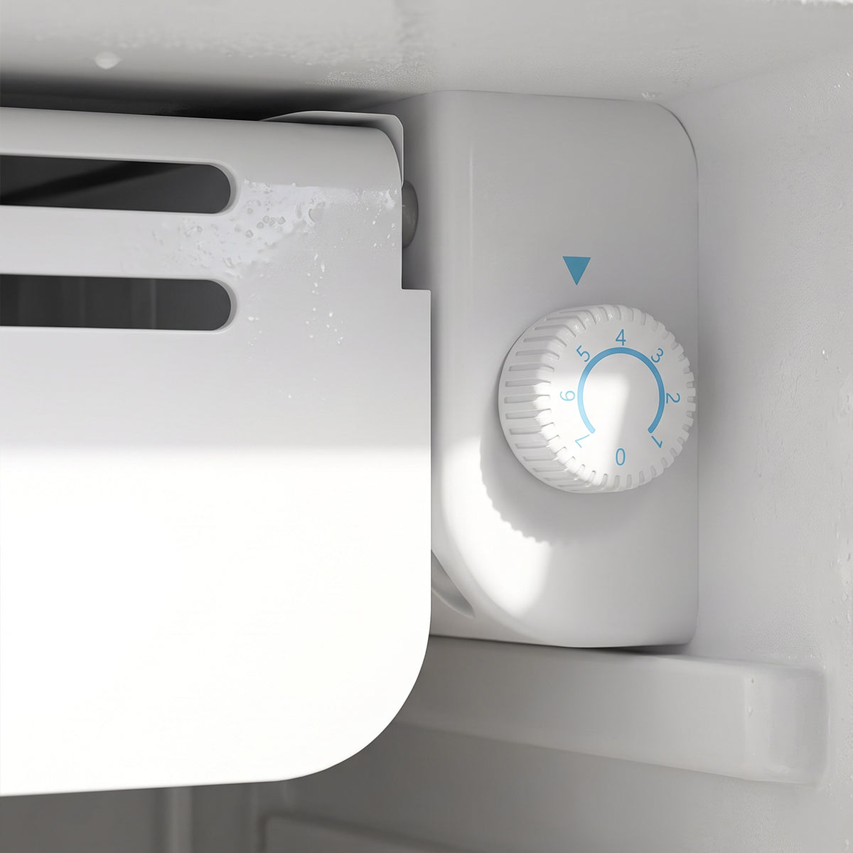 Close-up of the mini fridge chiller compartment thermostat dial on the interior wall.
