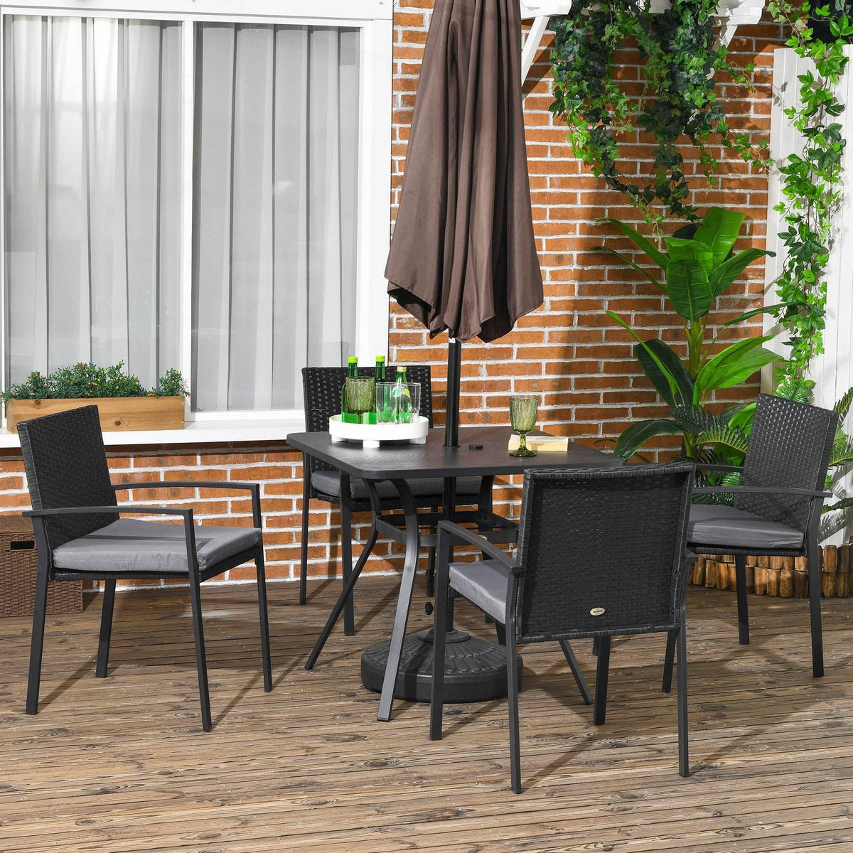 Black rattan outdoor dining set with four chairs, cushioned seats, and umbrella-hole table