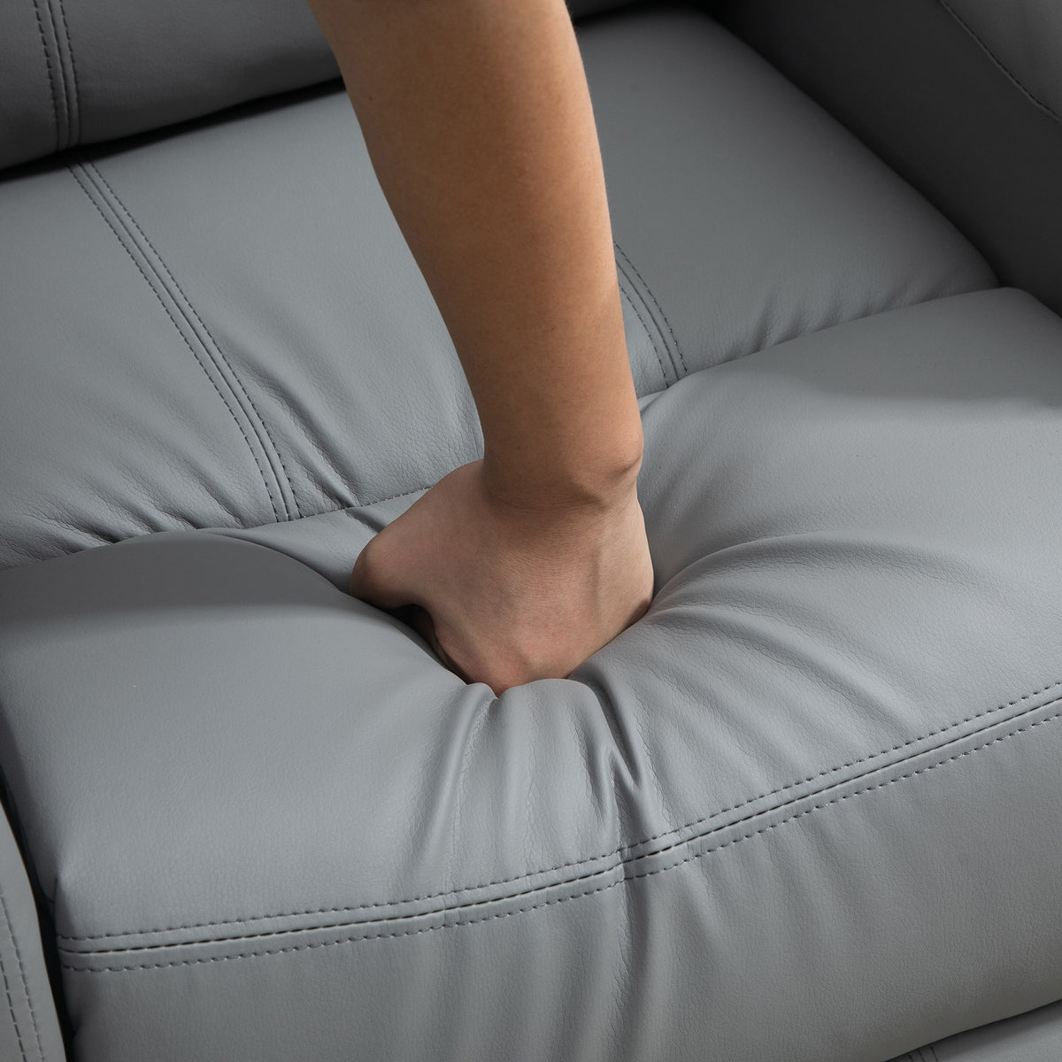 Grey cushioned recliner seat with stitched seams and foot resting on comfort platform