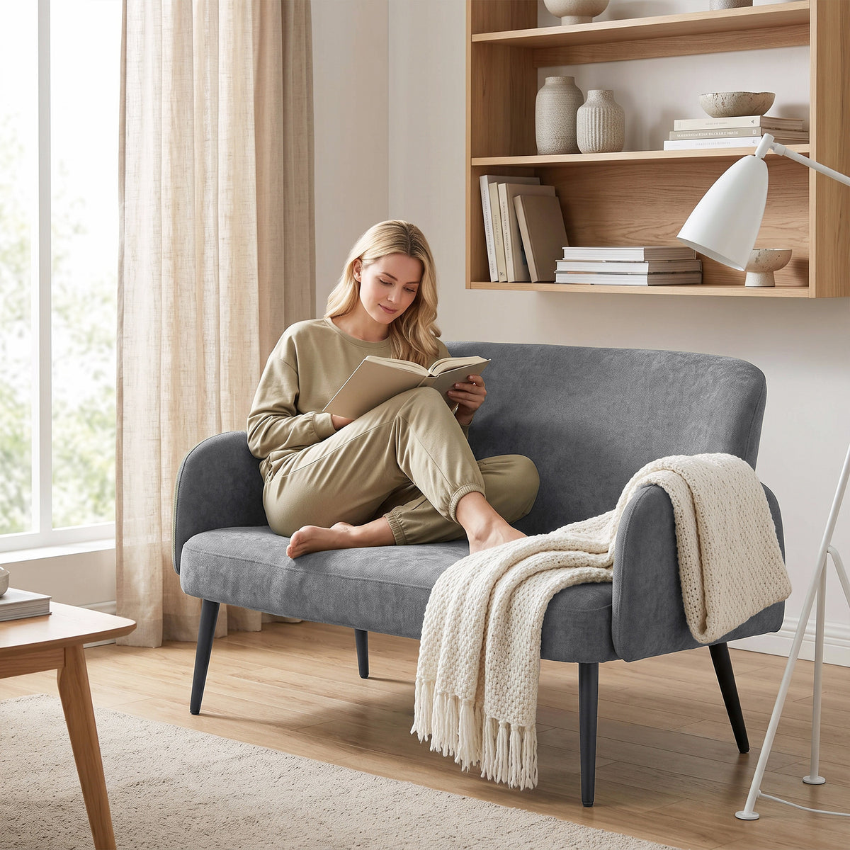 Light grey velvet two-seater sofa with deep seat, rounded arms, and dark legs