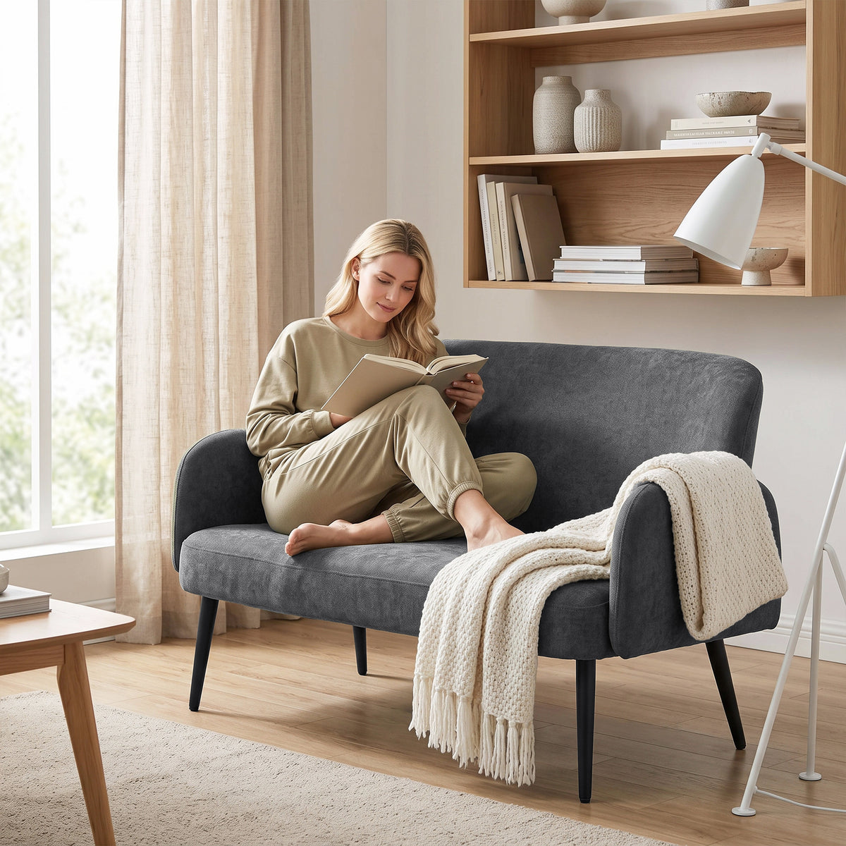 Dark grey velvet small sofa with wide seat, rounded arms, and tapered legs