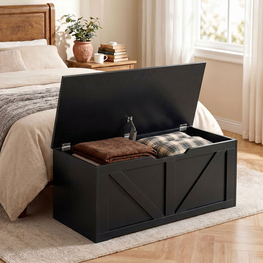 Black wood-effect storage bench with hinged lid open, showing soft items inside.
