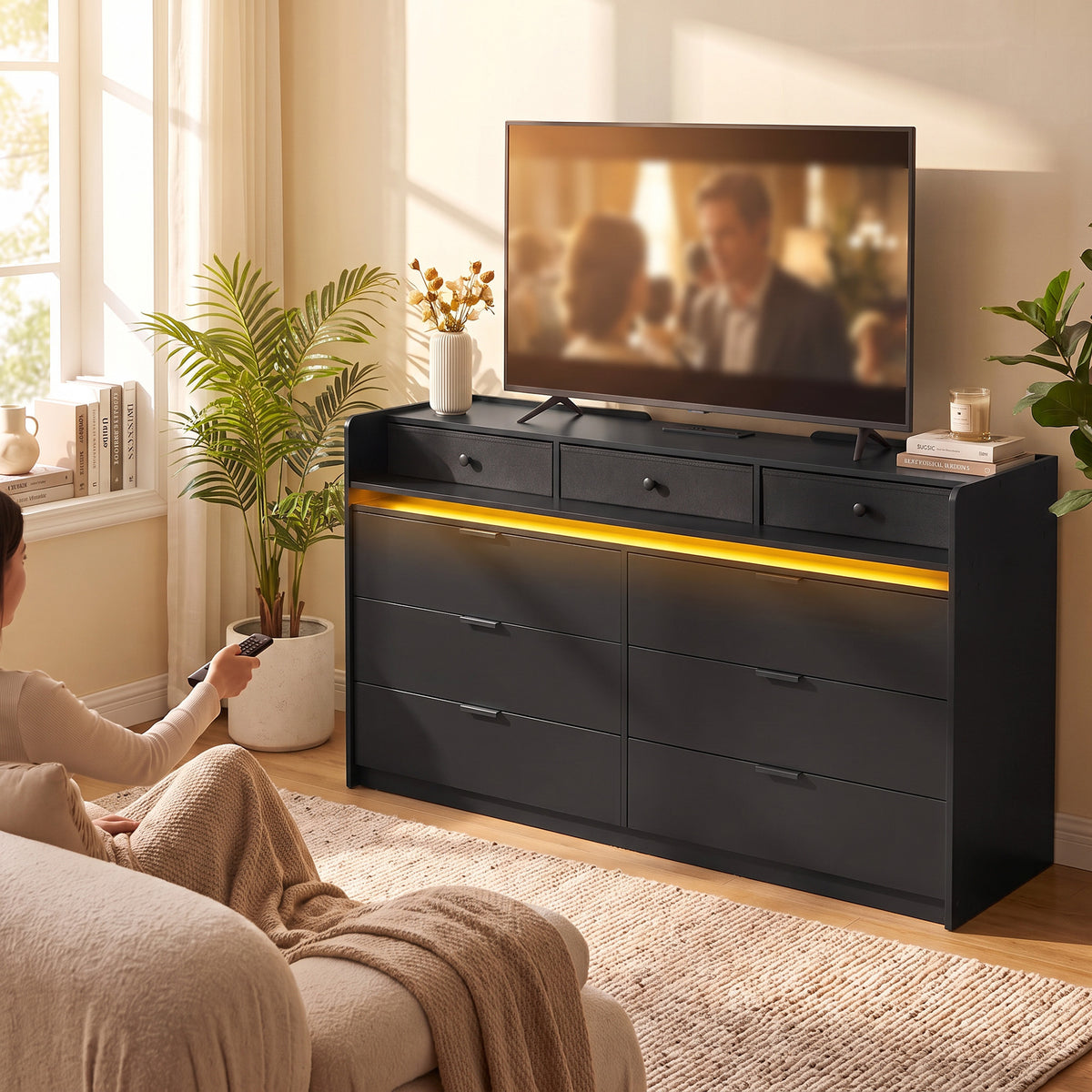 Black 9-drawer TV stand with warm yellow LED strip in a living room