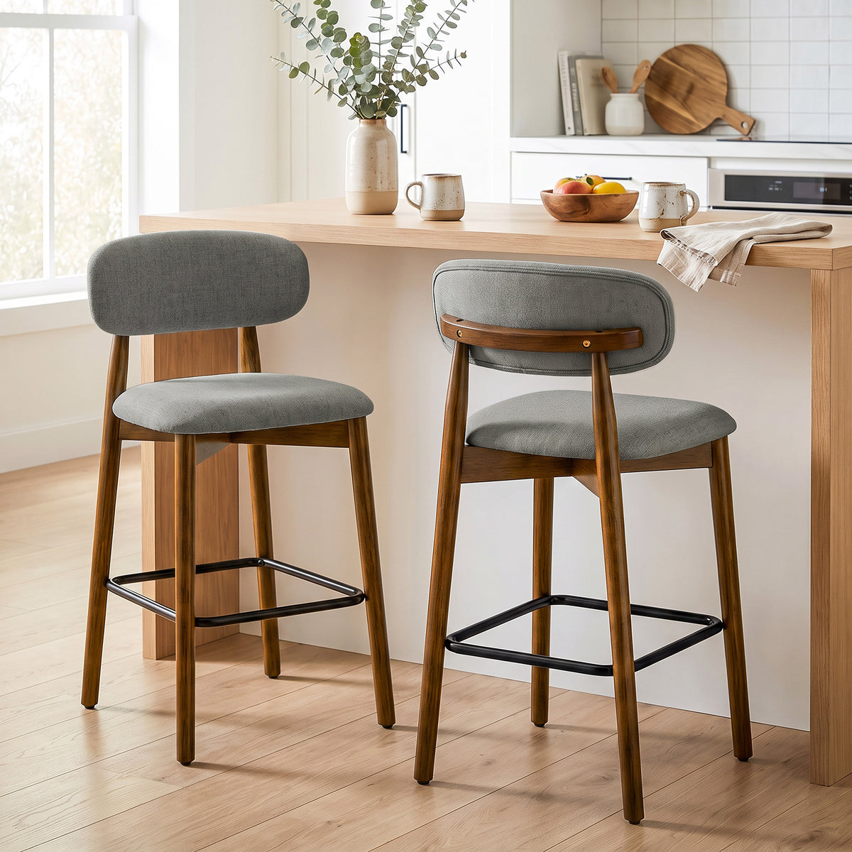 Set of 2 grey upholstered bar stools with curved back and black footrest bars