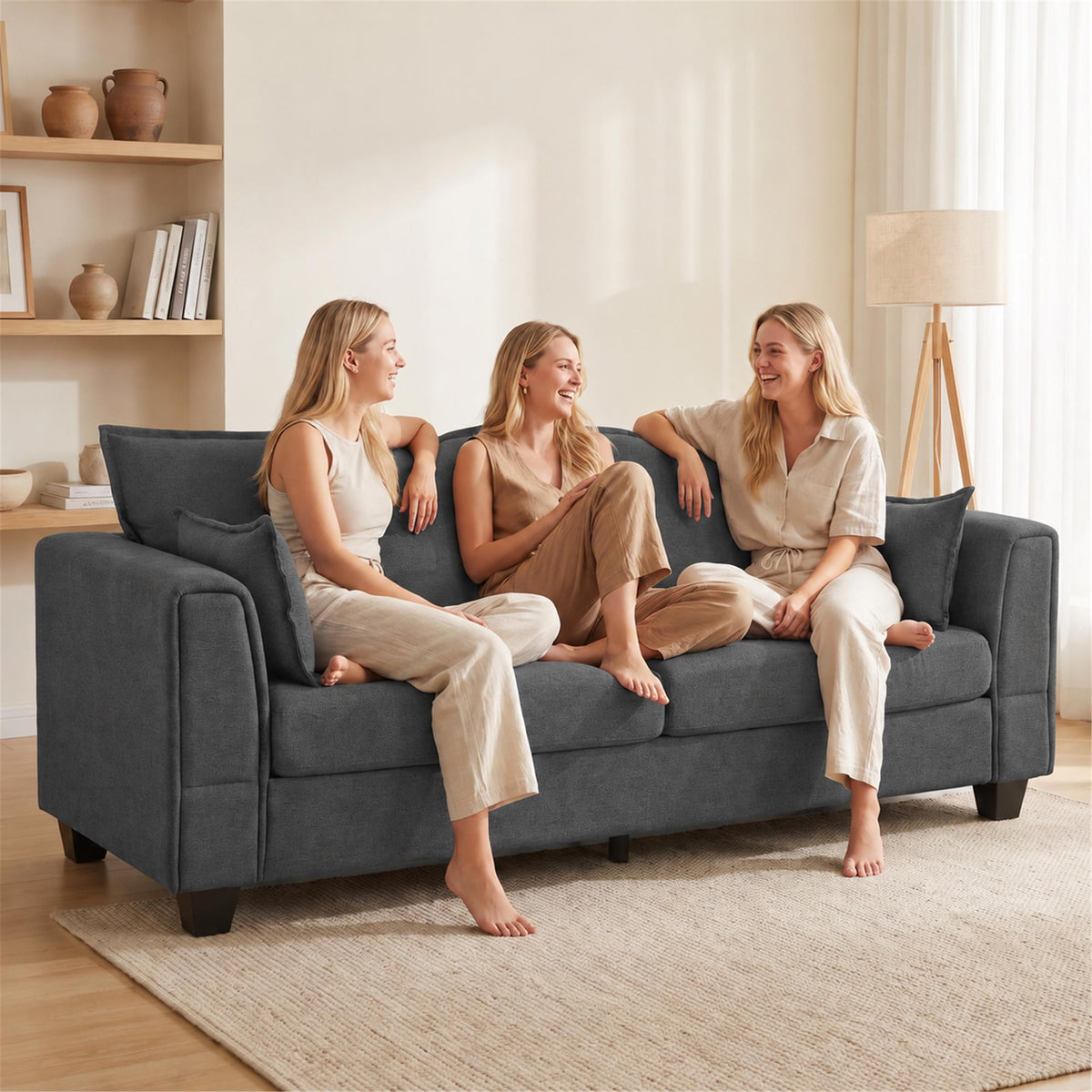 Dark grey 3-seater sofa with padded back and armrests, three people relaxing.