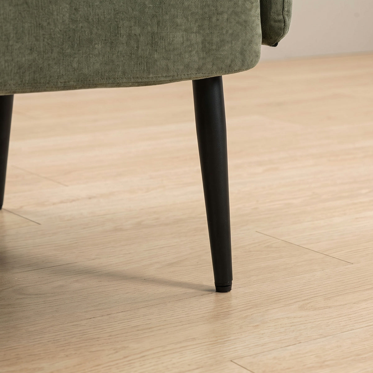 Close-up of green velvet sofa leg with black metal base