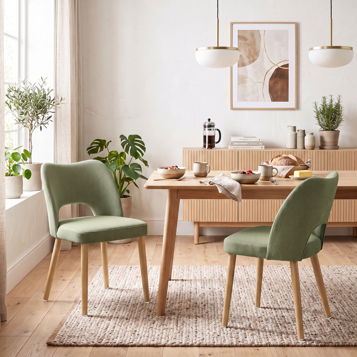 Set of 2 green upholstered dining chairs with curved backs and light wood legs