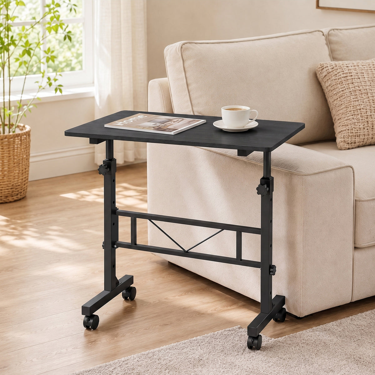 Adjustable overbed table beside sofa with black top and four rolling caster feet