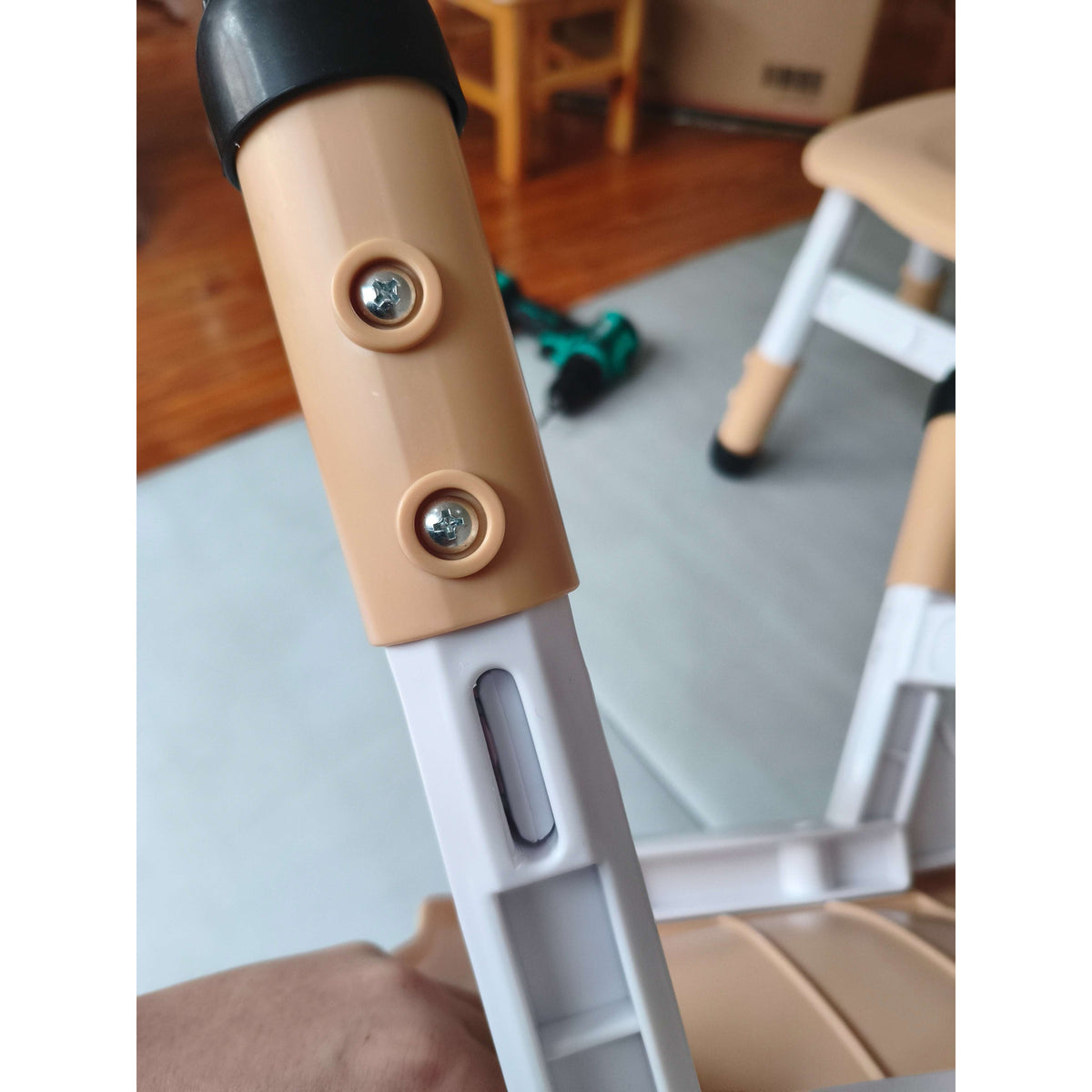Adjustable chair height bracket detail with two metal screws on light brown panel