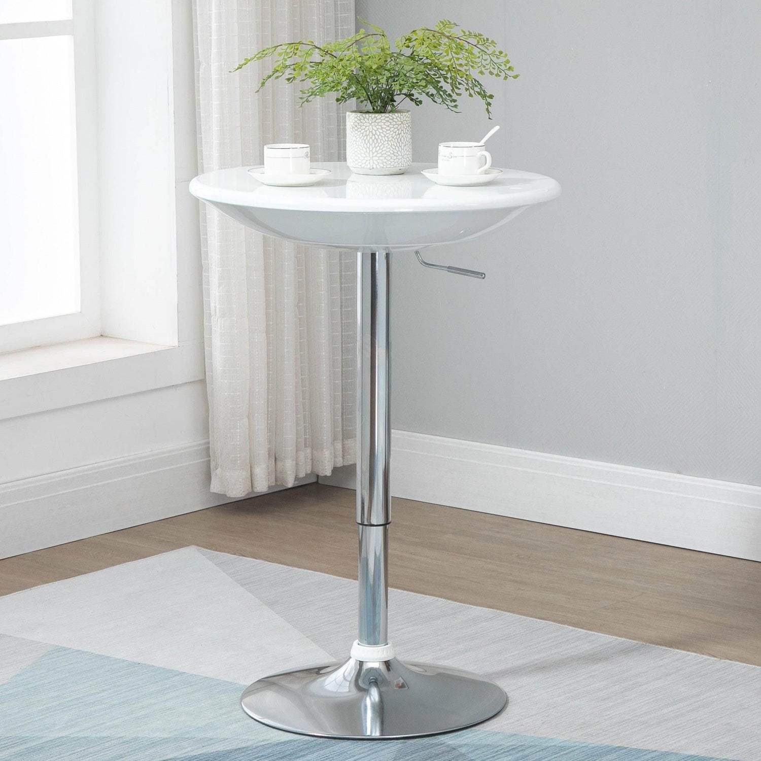 Adjustable white round bar table with chrome pedestal base and circular footrest.