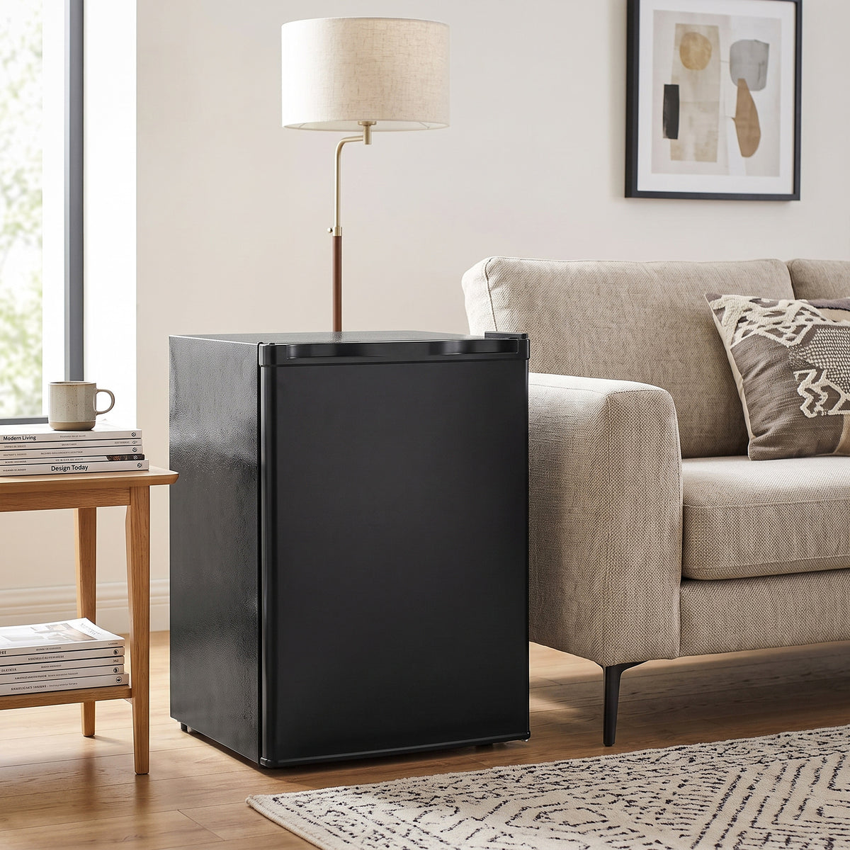 Black mini fridge standing beside sofa with door closed