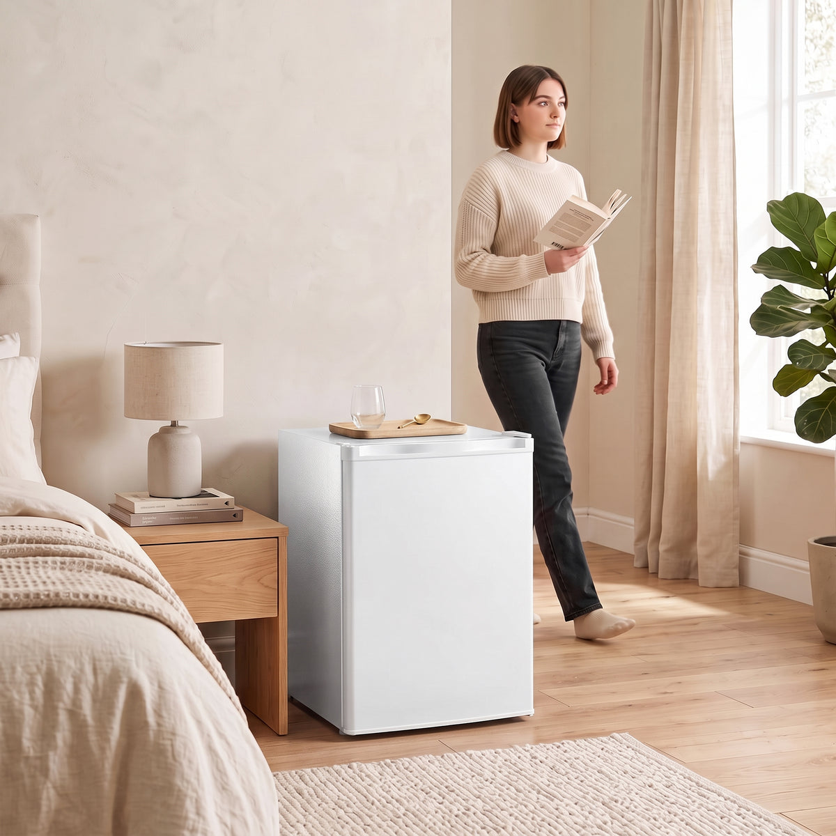 White mini fridge with chiller box in a living room, with a person reading nearby.