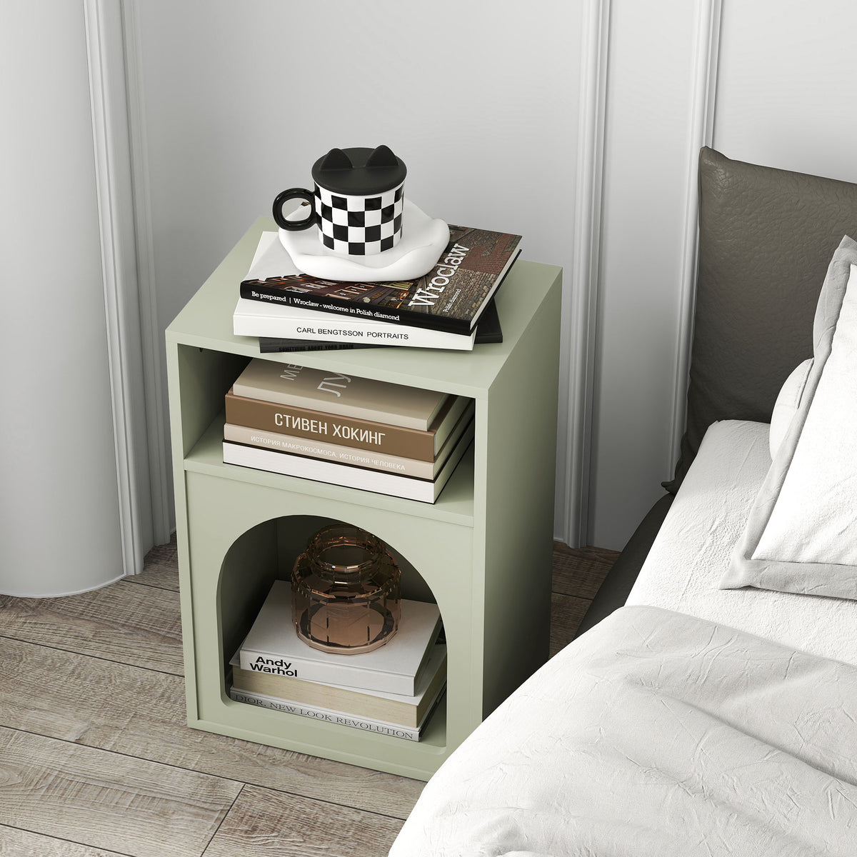 Green bedside table with open shelving and arched lower compartment for books and decor.