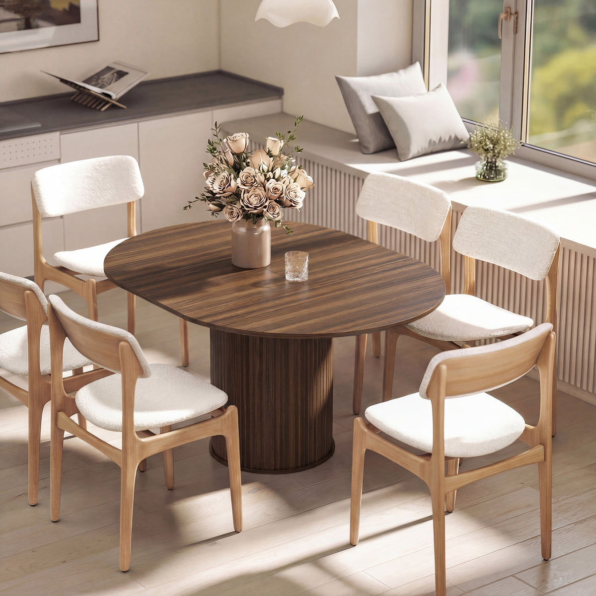 Round dining table with dark wood top and pedestal base, styled with chairs and flowers