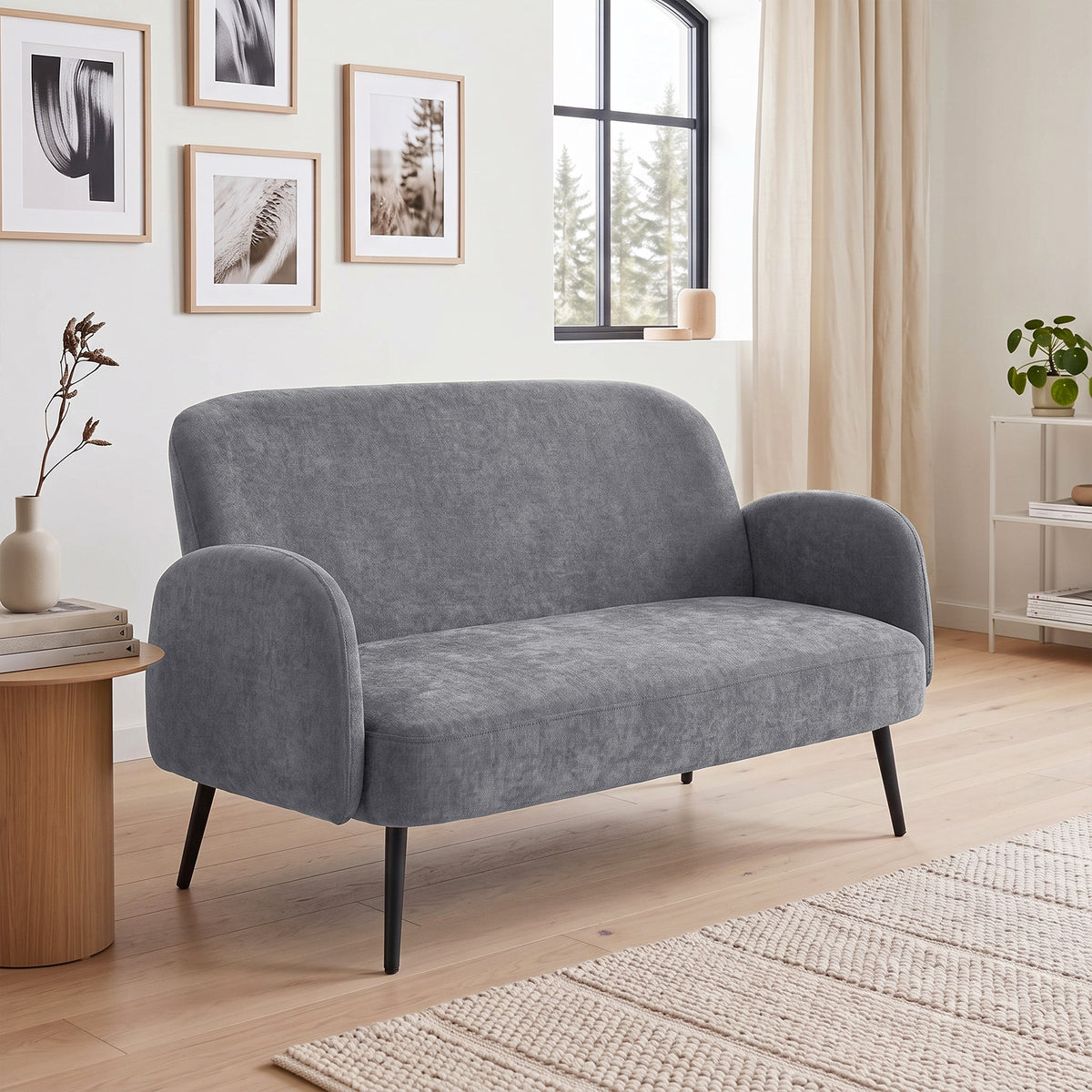 Light grey velvet two-seater sofa with rounded arms and dark tapered legs