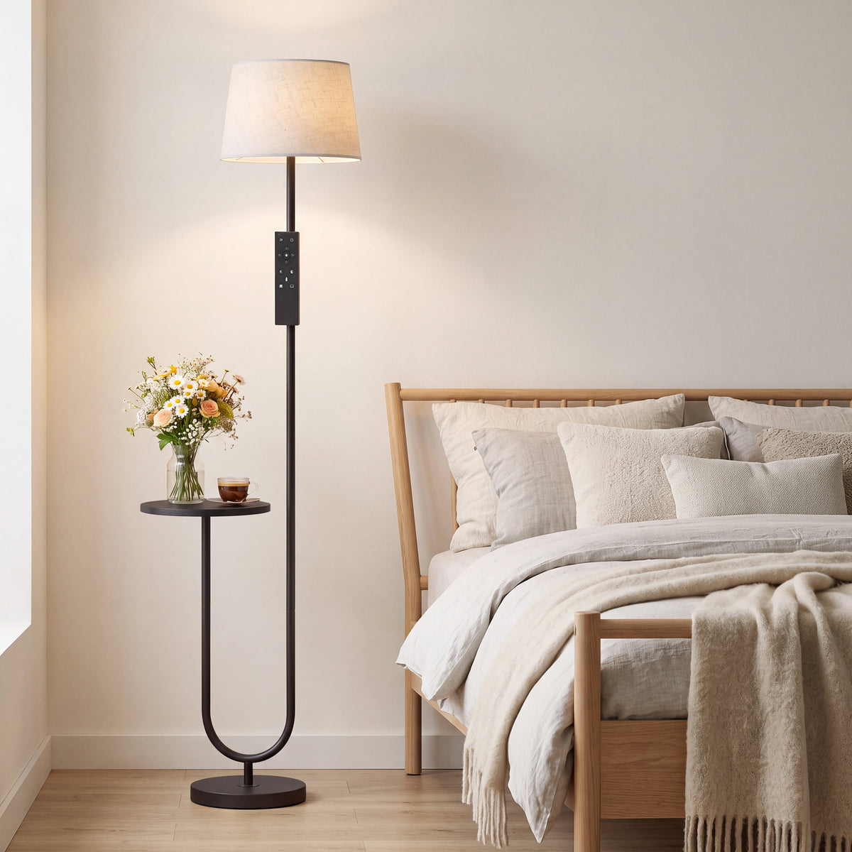 Tall floor lamp with linen shade and round side shelf beside bed