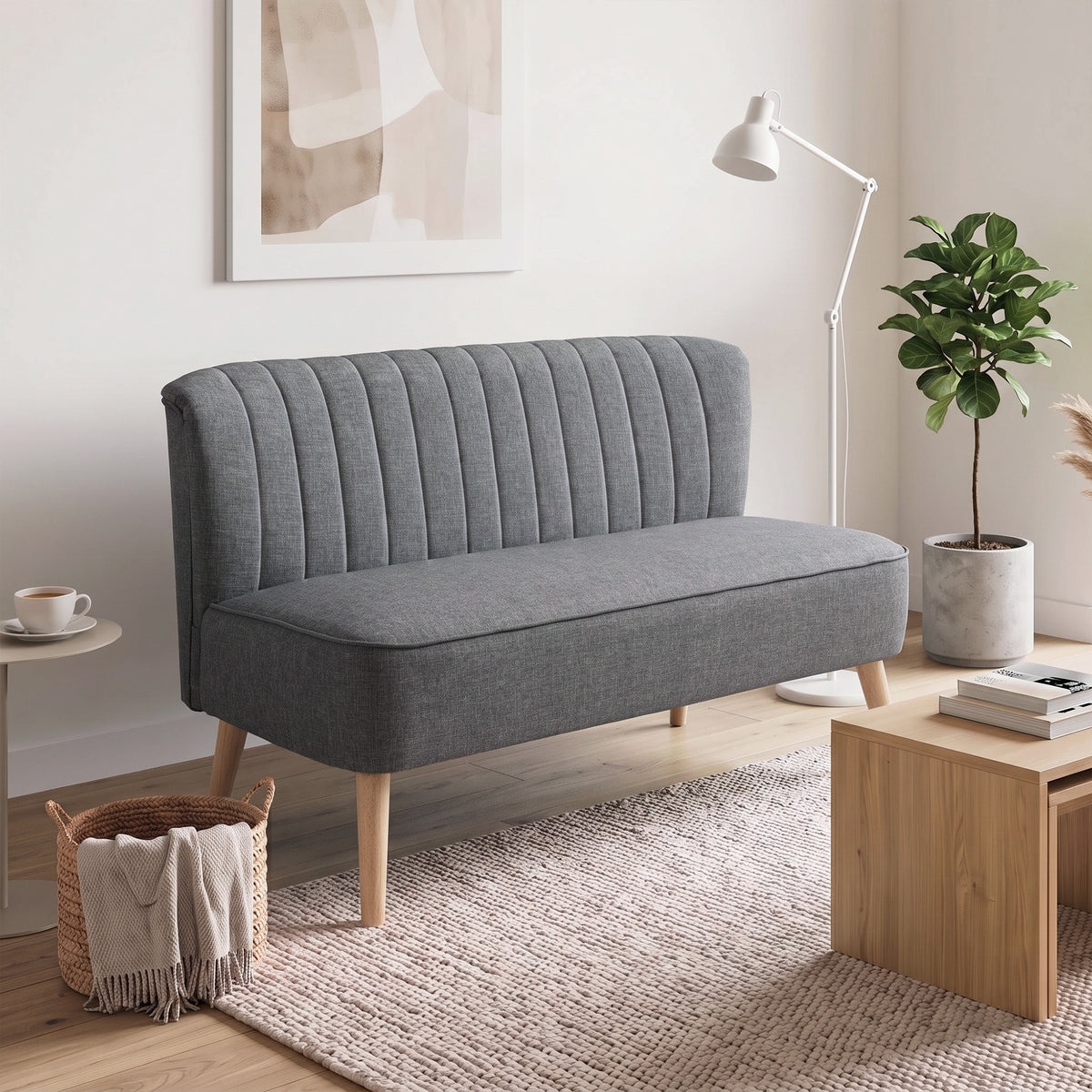 Dark grey loveseat sofa with tufted back and light wood legs on rug