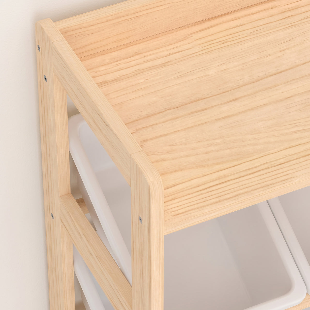 Light wood cabinet side panel and top shelf edge over white plastic bins