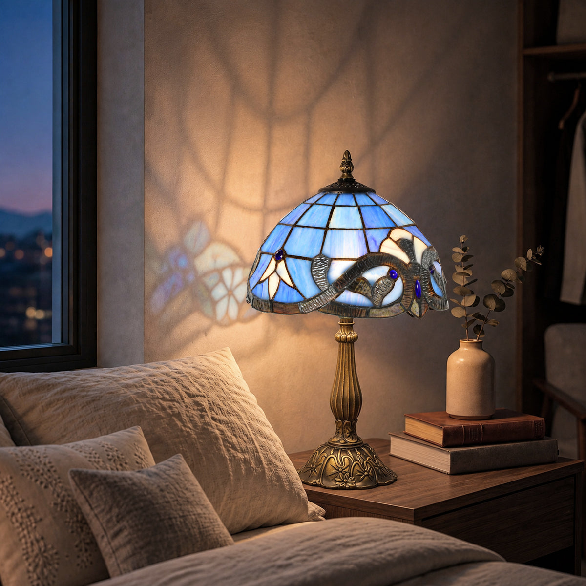 Blue stained glass table lamp with antique bronze base on a nightstand beside the bed